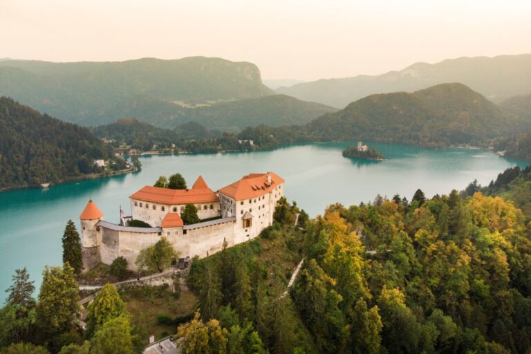 Aerial view of Bled Castle overlooking Lake Bled and the island at sunset.