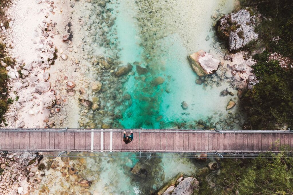 Aerial view of the turquoise Soča River and a scenic bridge.