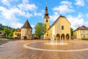 Main square in Tarvisio with church, fountain and colourful buildings