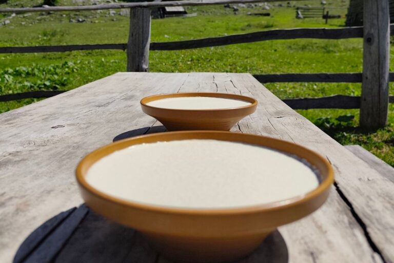 Two clay bowls of sour milk on a wooden bench.