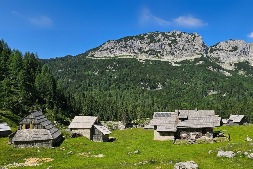 Wooden huts on the Laz pasture below a rocky ridge.